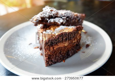 brownies cake on the table / piece of chocolate cake cocoa with nut and icing sugar on top view brownies slice on white plate the wooden table background