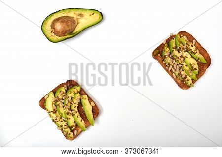 Toast With Avocado Slices, A Mixture Of Seeds On A White Background. Healthy Snack Tomorrow. The Con