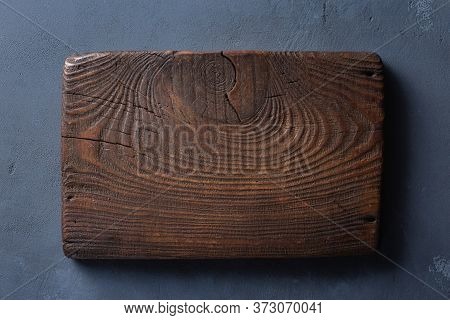 Rustic Wood Cutting Board On Dark Table. Top View