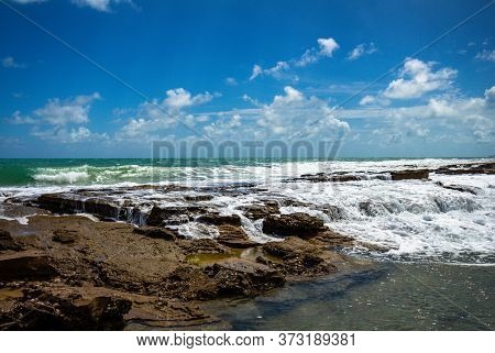 Coral Reef At The Edge Of The Sea Bathed In Sea Foam. Small Waterfalls Of Rocks Below The Horizon.