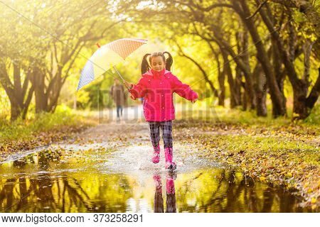 Adorable Toddler Girl With Colorful Umbrella Outdoors At Autumn Rainy Day