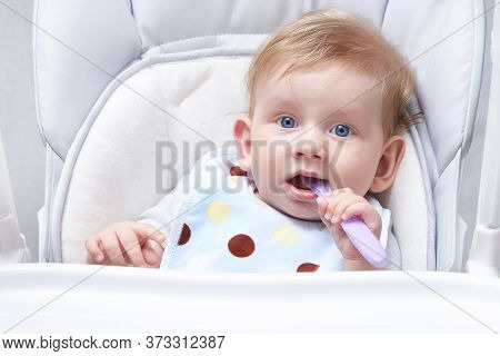 Blond Baby Eats First Lure. Holding A Spoon Close Up