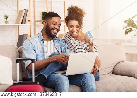 Planning Vacation Concept. Black Spouses Using Laptop And Credit Card Booking Tickets And Hotel Onli