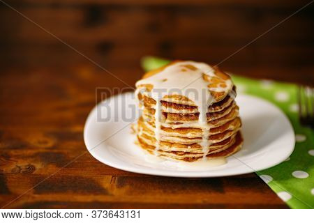 Condenced Milk Being Poured On A Stack Of Pancakes.