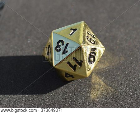 Golden Metallic D20 Twenty Sided Dice On Foam Surface In Bright Sunshine