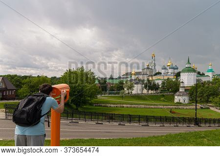 A Boy Tourist In A Blue T-shirt Stands On The Observation Platform Looking Through A Telescope, Bino