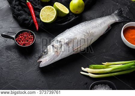 Seabass With Spices And Herbs Ingredients  On Black Background Side View Space For Price.