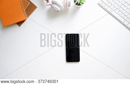 Modern White Office Work Table With Smartphone Mock Up Keyboard, Headphones,notepad Top View.