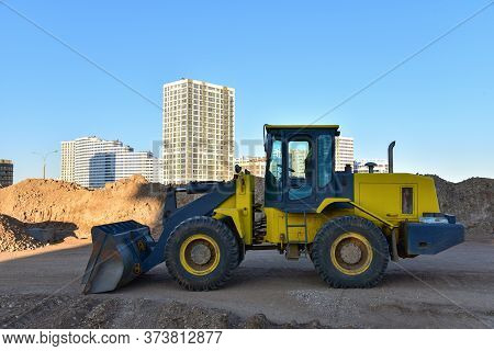 Front-end Loader Working At Construction Site. Earth-moving Heavy Equipment For Road Work. Public Wo