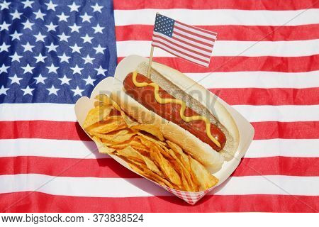 Hot Dog. Hot Dog with Potato Chips and an American Flag on an American Flag place mat. Hot Dogs are enjoyed World Wide by hungry people. 
