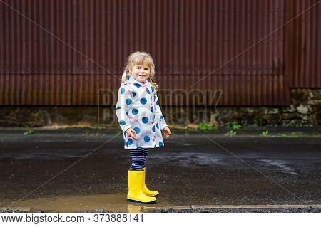 Little Toddler Girl Wearing Yellow Rain Boots, Running And Walking During Sleet On Rainy Cloudy Day.