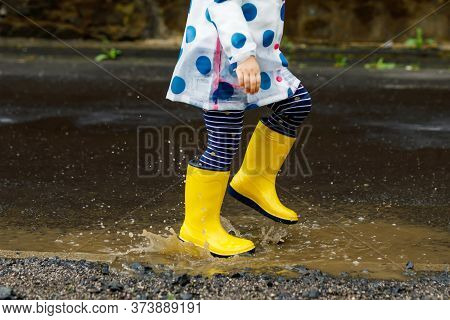 Little Toddler Girl Wearing Yellow Rain Boots, Running And Walking During Sleet On Rainy Cloudy Day.