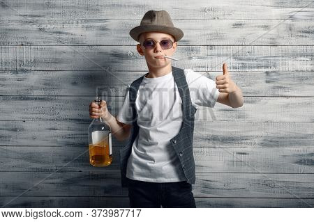 Little boy in stylish hat holds bottle