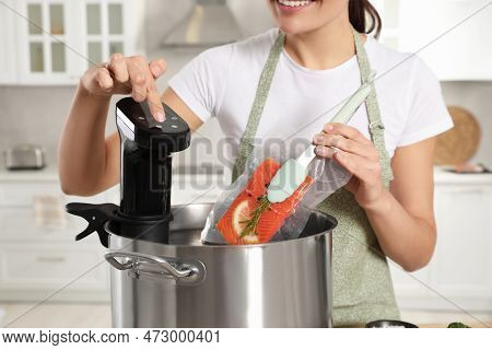 Woman Putting Vacuum Packed Salmon Into Pot And Using Thermal Immersion Circulator In Kitchen, Close
