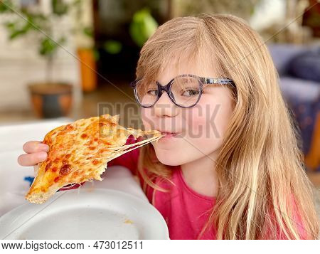Little Preschool Girl Eating A Piece Of Pizza. Happy Child Biting Pizza With Cheese.