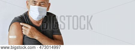 Male Senior Smiling After Receiving Vaccine. Old Man Showing Arm With Bandage, Patch After Vaccine F