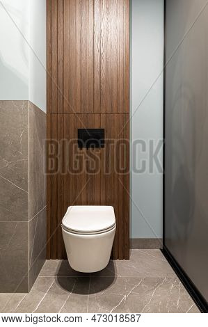 Modern Bright Bathroom With White Toilet Seat On Wooden Lamela Wall. Mirror On Grey Wall.