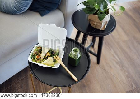 Close Up Of Take Away Food In White Container With Wooden Fork And Plactic Bottle Of Green Smoothie.