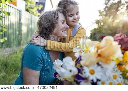 Cute Granddaughter Hugging Her Happy Grandmother. The Hugs Of An Elderly Woman And A Little Girl Aga
