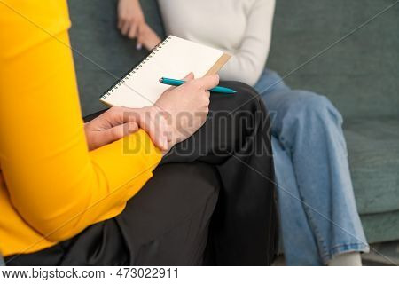 Close-up Of A Notebook And Pen On The Lap Of A Female Consultant, Psychologist, Journalist, Lawyer.