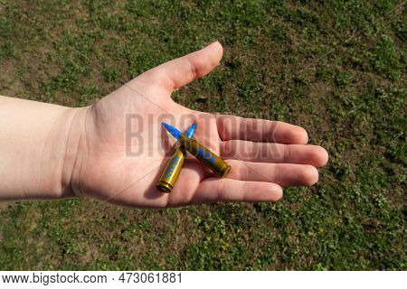 Two Yellow-blue Rifle Cartridges With The Inscription Stop War In Hand Against The Background Of Gre