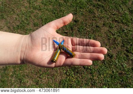 Two Yellow-blue Rifle Cartridges With Inscription Stand With Ukraine In Hand Against Background Of G