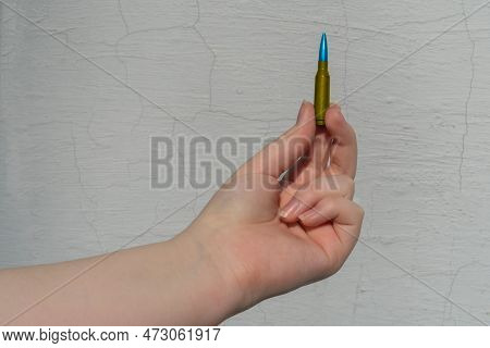 A Yellow-blue Rifle Cartridge In A Hand Against A White Wall (national Symbols Of Ukraine). The Conc