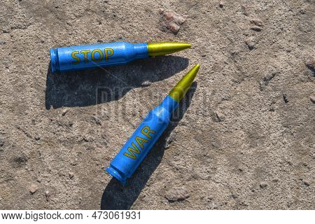Two Yellow-blue Rifle Cartridges With The Inscription Stop War Lie On A Concrete Surface (close-up).