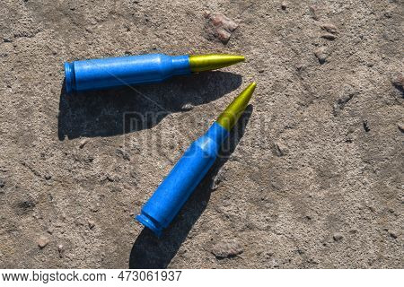 Two Yellow-blue Rifle Cartridges (the National Symbol Of Ukraine) Lie On A Concrete Surface (close-u