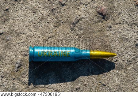 A Yellow-blue Rifle Cartridge With The Inscription Ukraine Lies On A Concrete Surface (close-up). Th