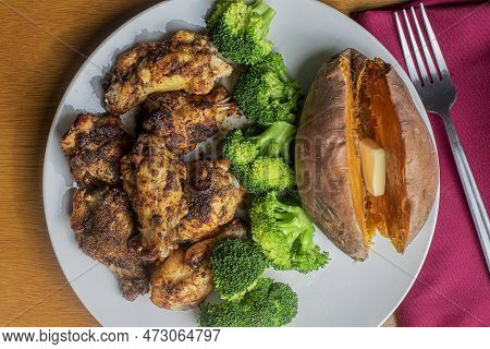 Chicken Wings Served With Broccoli And A Sweet Potato.