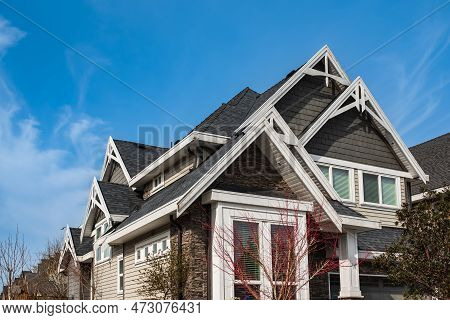 Roof Shingles On Top Of The House Against Blue Sky. Dark Asphalt Tiles On The Roof Background. Black