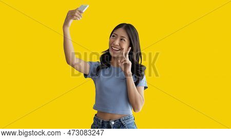 Cheerful Young Woman Taking A Selfie With A Mobile Phone And Raising Two Fingers, Portrait Of Happy 
