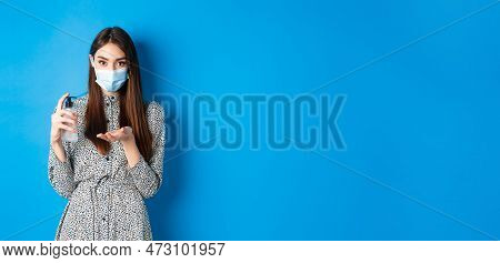 Covid-19, Social Distancing And Healthcare Concept. Beautiful Girl In Medical Mask Using Hand Sanizi