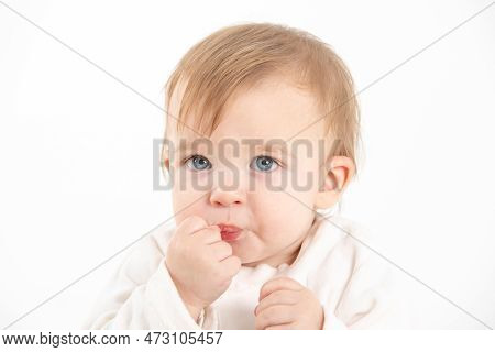 Stock Studio Photo With The White Background Of A Baby's Face With The Hand In The Mouth