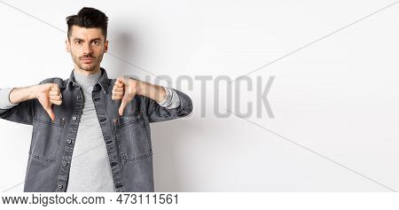 Very Bad. Serious Man Showing Thumbs Down And Look At Camera With Pokerface, Telling No, Disapprove 