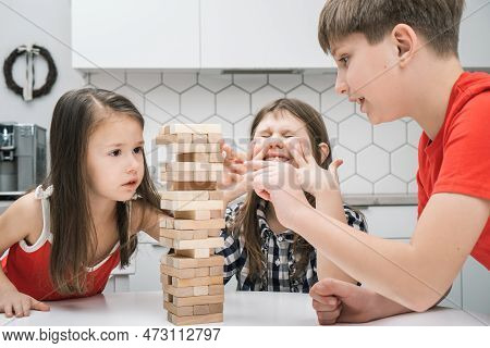 Nervous And Worried, Passionate Kids Playing Board Balance Wooden Brick Tower Game Together. Little 