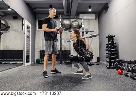 A Woman Exercising In An Electric Muscular Suit Stimulates Exercise In A Gym. A Young Female In An E