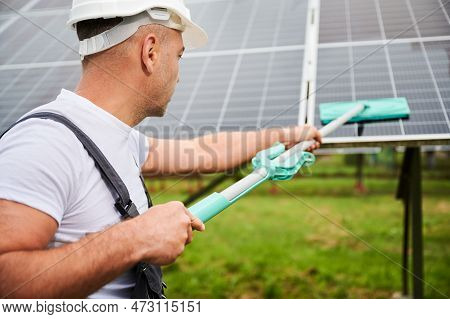 Close Up View Of Adult Worker Cleaning Pv Battery By Mop. Knowledgeable Man Taking Care About Green 