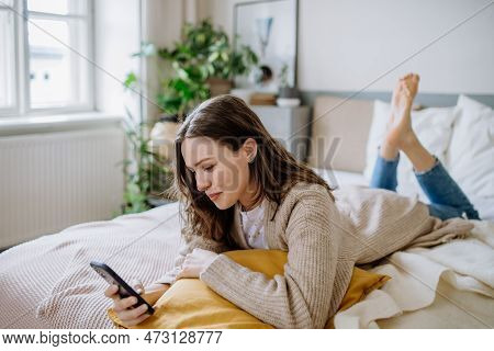 Young Woman Scrolling Her Smartphone In The Apartment.