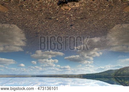 Lake Surrounded By A Rocky Shore, Mountains With Forest On Background.reflection Of White Clouds In 