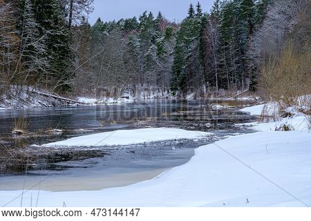 River Salaca With Snow And Floating Ice. Cold Winter Time. Tree Reflections In Dark Water. Skanaiska
