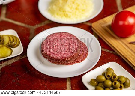 Salami On A Plate Close-up. Various Ingredients For Making Pizza.