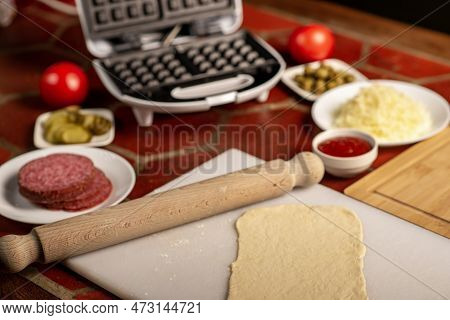 Cooking Pizza Waffle, Piffle. Waffle Iron And Yeast Dough For Pizza And Various Ingredients - Salami