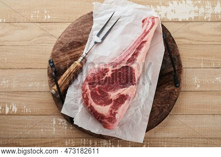 Fresh Tomahawk Raw Steak. Dry Aged Raw Tomahawk Beef Steak With Herbs And Salt On Old Wooden Backgro
