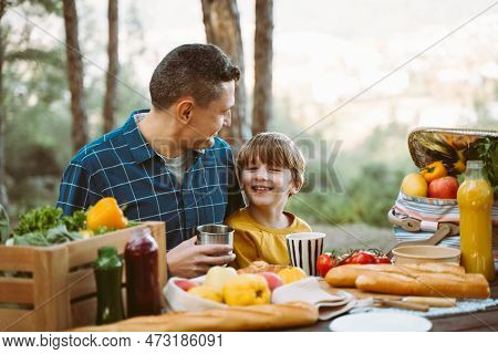 Father Hugs His School Boy Son On A Family Picnic In Mountains Forest Park. Child Kid And His Dad Ta