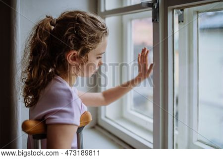 Little Girl With Broken Leg Looking Trough Window.