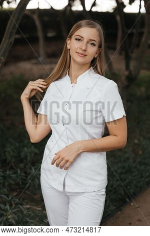 Smiling Confident Female Doctor With Lab Coat On Standing. Practician Woman Wearing White Hospital U