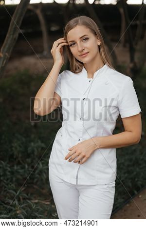 Smiling Confident Female Doctor With Lab Coat On Standing. Practician Woman Wearing White Hospital U