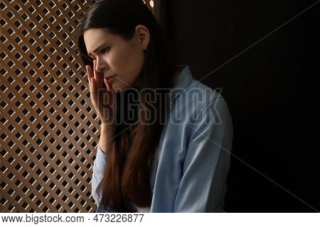 Upset Woman Listening To Priest During Confession In Booth